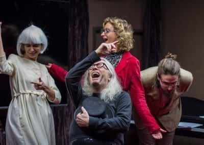 four people performing in a theater with excited expressions