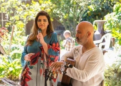 a woman holding a mic and a man holding a guitar in an outdoor location