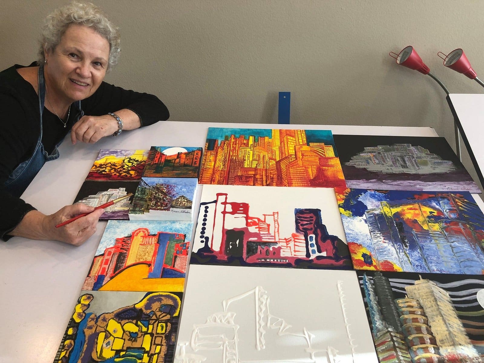 Miriam Libhaber posing next to her artwork spread on the table.