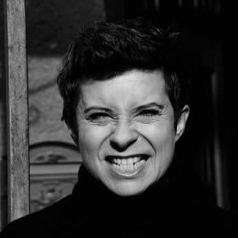 Dorota Abbe Dorota Abbe smiling with a scrunched face in a black-and-white portrait.