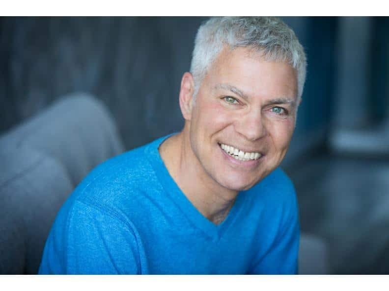 Steve Budd Steve Budd, a smiling man with short gray hair, wearing a bright blue sweater, seated indoors with a softly blurred background.