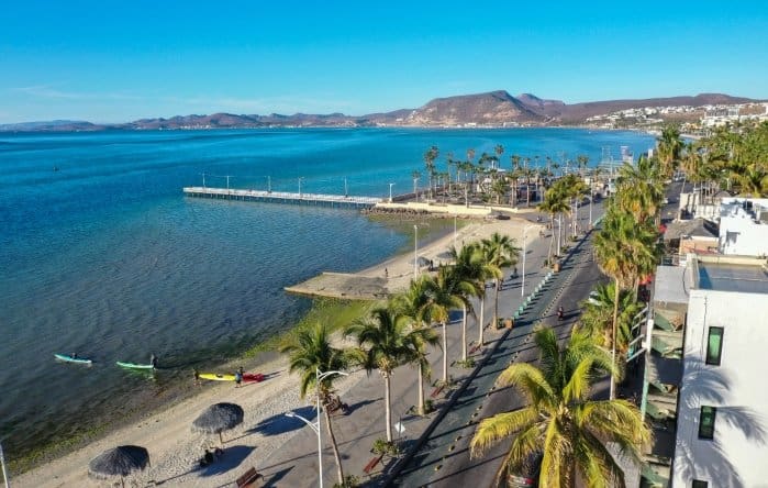 A photograph of La Paz, a beach town with palms, surfers, ocean and mountains