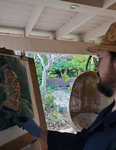 Oleg Tsank painting a Yiddish portrait of a man on an easel inside the studio at Yiddishland California.